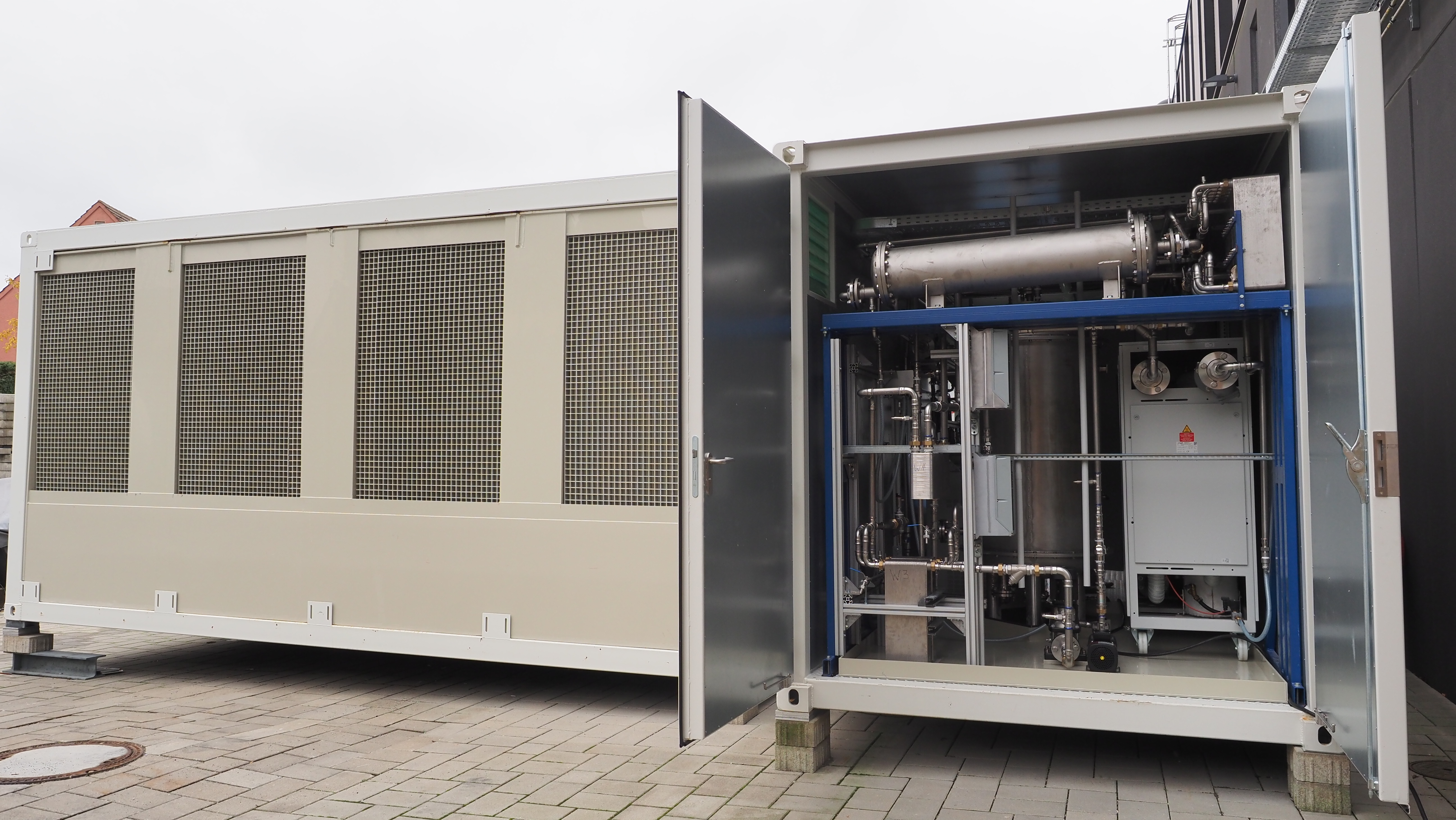 DAC demonstration plant consisting of two containers in the ZSW courtyard. One container is open and shows stainless steel tanks, pipework and measurement technology.